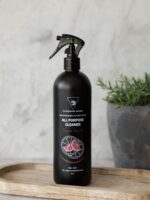 Cleaning Mama plant-based Fresh Scent All Purpose Cleaner in a black spray bottle displayed on a wooden tray beside a potted plant.