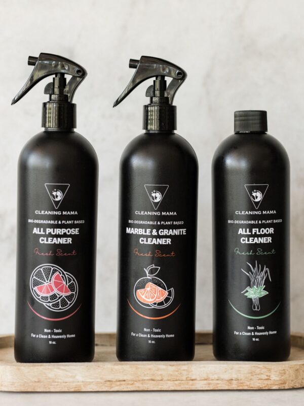 Close-up of the Cleaning Mama Fresh Scent trio featuring All Purpose, Marble & Granite and All Floor Cleaner in black bottles on a wooden tray.