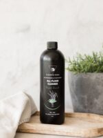 Cleaning Mama plant-based Fresh Scent All Floor Cleaner displayed on a wooden tray beside a white towel and potted plant.
