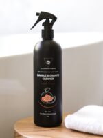 Cleaning Mama plant-based Fresh Scent Marble & Granite Cleaner displayed next to a white towel on a wooden table beside a bathtub