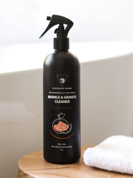 Cleaning Mama plant-based Fresh Scent Marble & Granite Cleaner displayed next to a white towel on a wooden table beside a bathtub