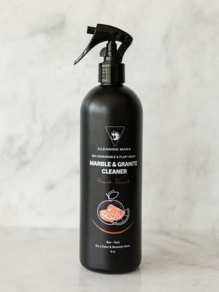 Cleaning Mama non-toxic, plant-based Fresh Scent Marble & Granite Cleaner in a black spray bottle sitting on a marble countertop.