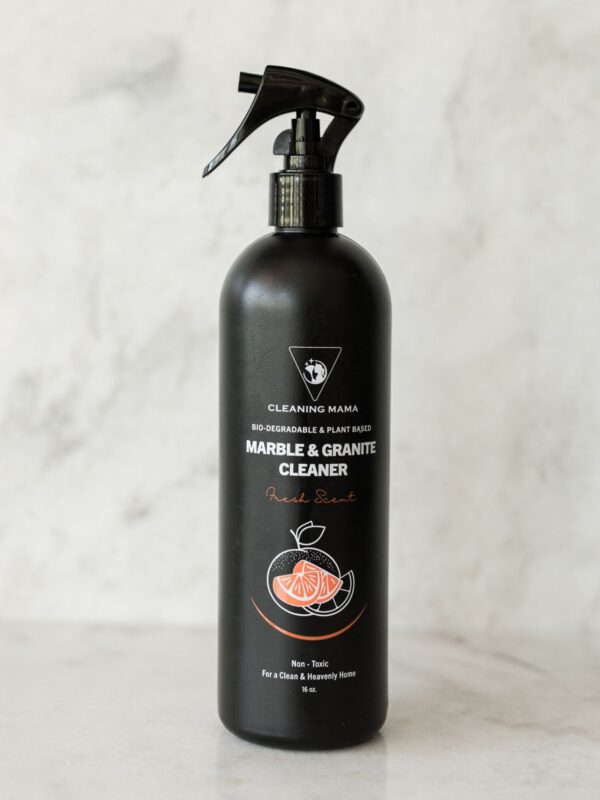 Cleaning Mama non-toxic, plant-based Fresh Scent Marble & Granite Cleaner in a black spray bottle sitting on a marble countertop.