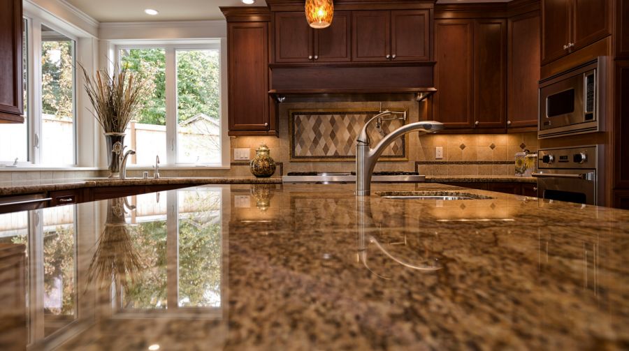 Polished natural stone kitchen countertop with dark wood cabinetry and stainless steel faucet