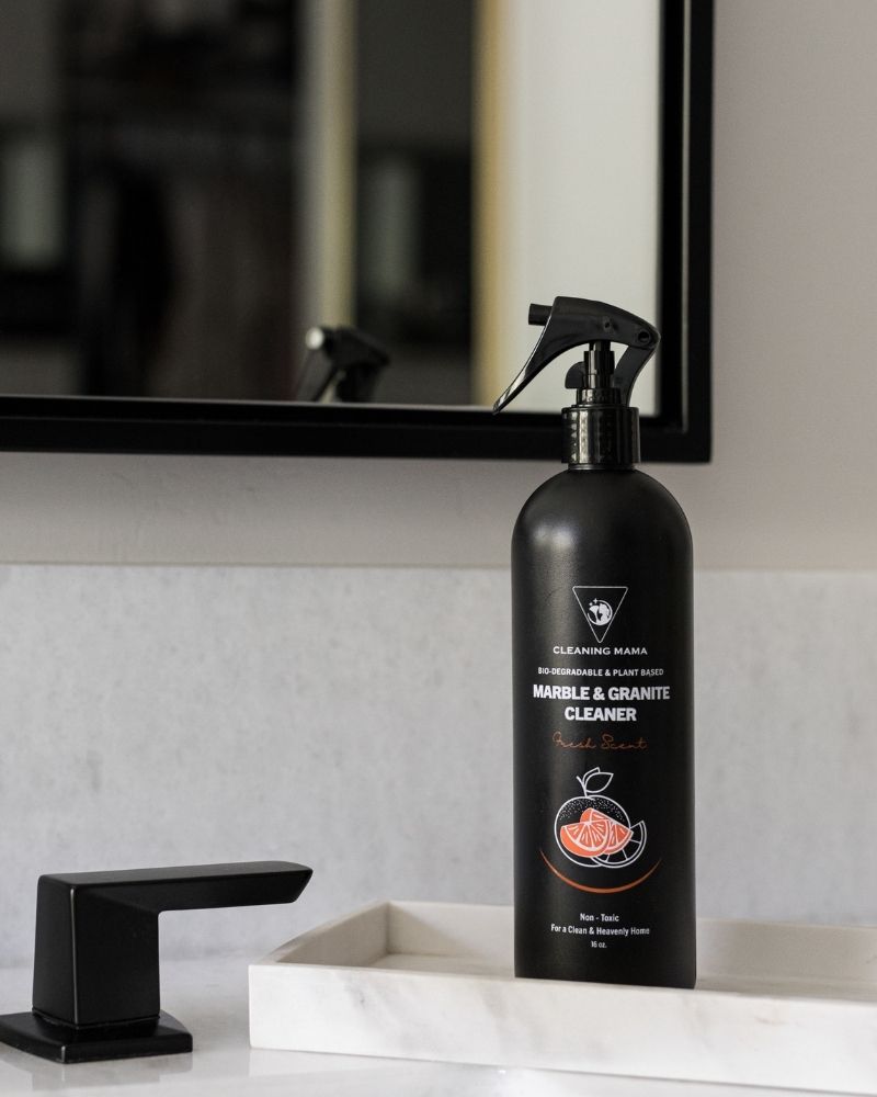 Cleaning Mama Marble & Granite Cleaner on a bathroom sink beside a black faucet