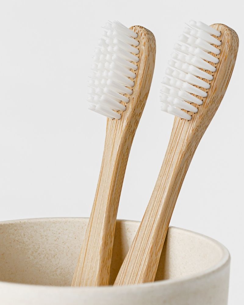 Two bamboo toothbrushes standing in a bathroom cup