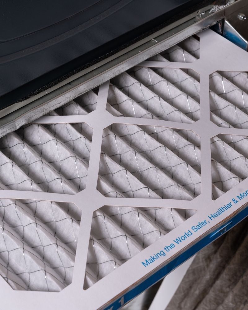 Close-up of a pleated HVAC air filter being checked before the heating season