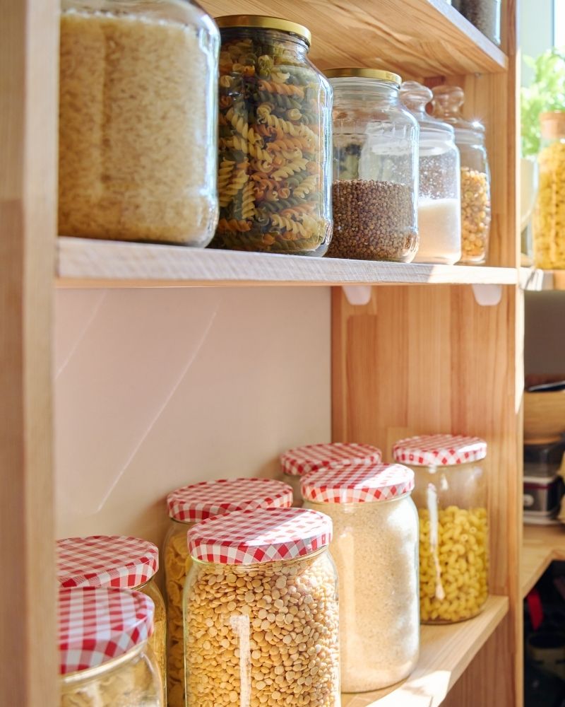 Organized pantry shelves with dry goods stored in glass jars